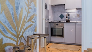 Una cocina moderna con armarios blancos, una estufa a gas y un respuesto de azulejos. Hay velas sobre una mesa de madera y un cuadro abstracto grande en la pared.