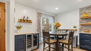 Une cuisine moderne avec un coin repas, comprenant un îlot central, des chaises en bois et un four encastré.