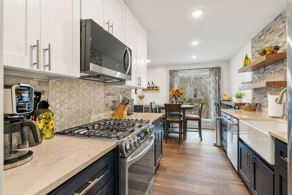 A modern kitchen with white cabinets, a stainless steel stove, and a large window.