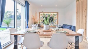 A dining area with a wooden table, white chairs, and a potted aloe vera plant. - Amazing home in Angerville-l'Orcher with WiFi (Angerville-l'Orcher)