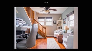 A living room with a staircase, a white sofa, a wooden coffee table, and a TV stand with electronic devices. - The Seapointe House. DISCOVER CAPE MAY. (North cape may)