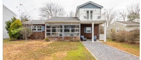 A two-story house with a front porch, a garage, and a gravel driveway.
