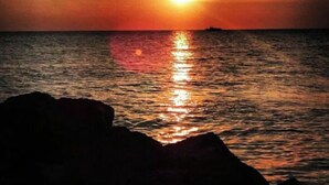 A sunset over the ocean with a silhouette of rocks in the foreground. - The Seapointe House. DISCOVER CAPE MAY. (North cape may)