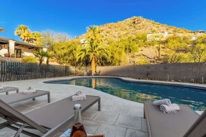 Un espace aménagé au bord de la piscine, avec des chaises longues, une bouteille et une clôture en bois.