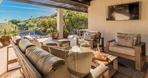 Un espace extérieur aménagé, abrité et doté d’un canapé, de chaises et d’une table, offrant une vue sur un paysage montagneux.