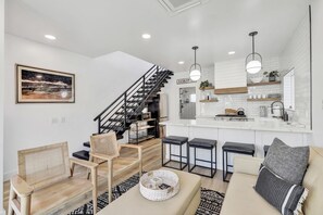 Un interior moderno con una escalera, una zona de cocina y espacios para sentarse.