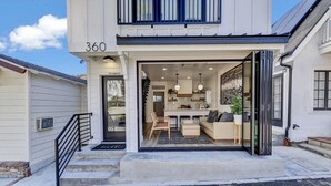 A modern two-story house with a visible kitchen, dining area, and a staircase leading to the upper floor. - Remodeled Rooftop Deck Home | Casino & Ocean Views (Avalon)