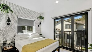 A bedroom with a bed, a window, a balcony, and a wall with text.