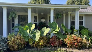 Une maison avec un porche, de grandes plantes et une pancarte indiquant «Bienvenue».