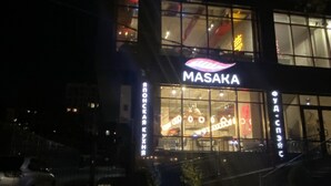 Un bâtiment sur lequel on peut voir, en lettres lumineuses bien visibles, l’inscription « MASAKA ».