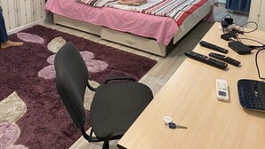 Une chambre à coucher avec un lit, un bureau, une chaise et une fenêtre avec des rideaux.
