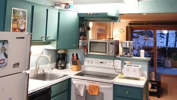 A kitchen with teal cabinets, a white stove, a microwave, and a refrigerator. - Condo near wiffletree chairlift! (Carrabassett Valley)