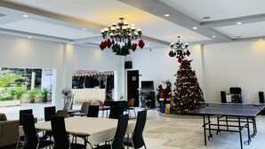 Un espacio interior amplio con una mesa de comedor, sillas, una mesa de ping pong y un árbol de Navidad.