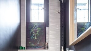 Ett badrum med en vit toalett, ett blått skåp, en vit handfat och ett fönster med galler.