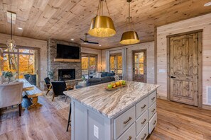 A spacious living area with a fireplace, a large island with drawers, and a ceiling fan.