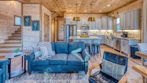 A cozy log cabin interior with a living room featuring a blue sofa and a dining area.