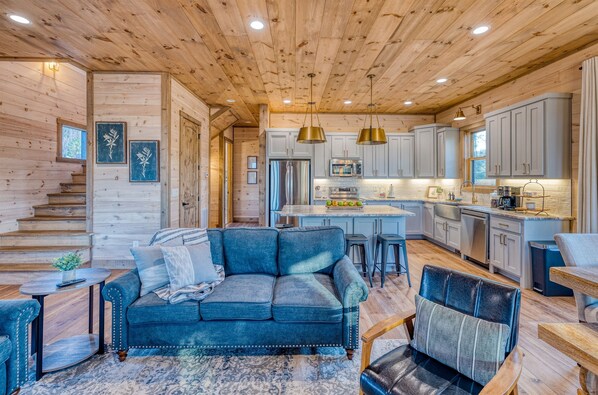 A cozy log cabin interior with a living room featuring a blue sofa and a dining area.