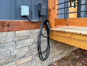 A stone wall with a wooden bench and a metal electrical box mounted on it.