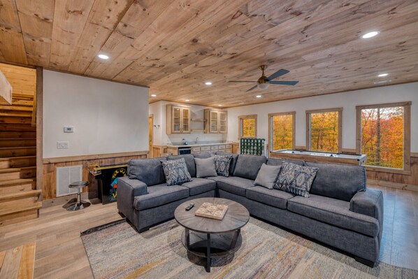 A modern living room with a sectional sofa, a coffee table, and a ceiling fan.