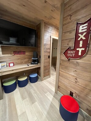 A wooden interior with an exit sign, a shelf with gaming controllers, and a sign stating "Every day is game day."