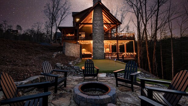 A lodge with a stone fireplace, outdoor seating, and a starry night sky.