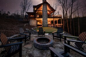 A lodge with a stone fireplace, outdoor seating, and a starry night sky.