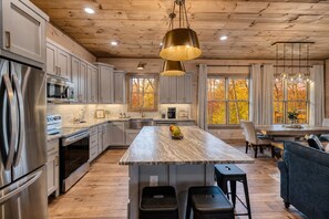 A modern kitchen with a large island, stainless steel appliances, and wooden flooring.