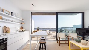A modern kitchen with white cabinetry and a dining area with a yellow table. - Superior Seafront Apartment, Porís 6 (Porís de Abona)