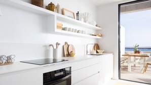 A modern kitchen with white cabinetry, a built-in oven, and a large window overlooking the sea. - Superior Seafront Apartment, Porís 6 (Porís de Abona)