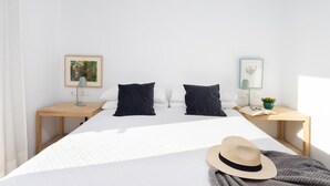 A hotel room with a large bed, two bedside tables, a lamp, a framed picture, a small plant, and a hat on the bed. - Superior Seafront Apartment, Porís 6 (Porís de Abona)