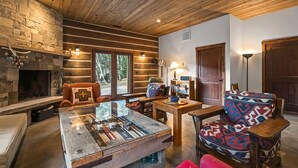 A cozy cabin interior with a stone fireplace, wooden beams, and rustic furniture. - Lake Side, Paddleboards, Firepit, Basketball! (Durango)