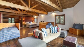 A spacious cabin with a high ceiling and exposed wooden beams. It features a cozy living area with a sofa, a bed, and a dining table. - Lake Side, Paddleboards, Firepit, Basketball! (Durango)