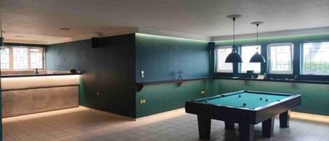 A pool table in a room with green walls and a window.