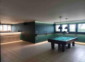 A pool table in a room with green walls and a window.