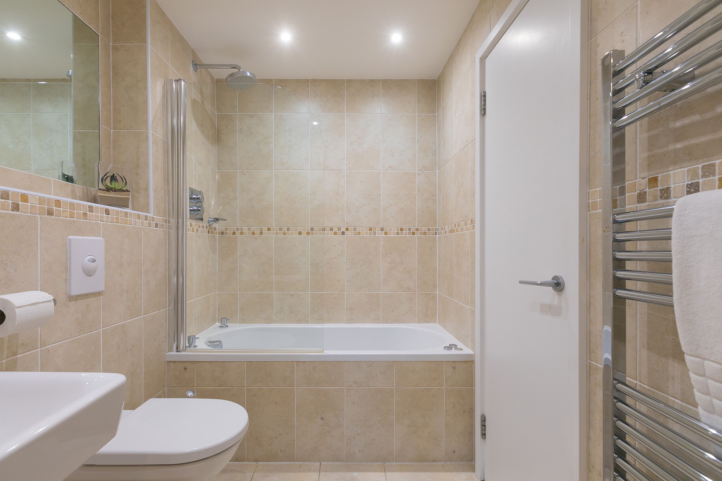 A bathroom with a bathtub, toilet, and a glass shower enclosure.