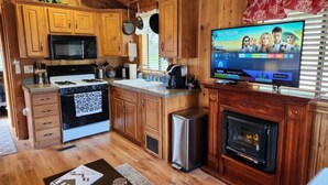 A kitchen with wooden cabinets, a microwave, stove, and a television displaying a show.