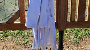 A wooden fence with a sign reading "TOWELS" and two white towels hanging on it.