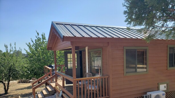 A small wooden cabin with a porch, a door, and windows.