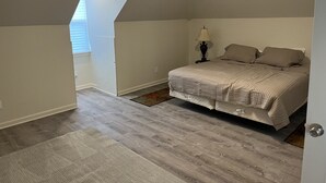 Un dormitorio con cama, mesita de noche, lámpara y ventana con persianas.