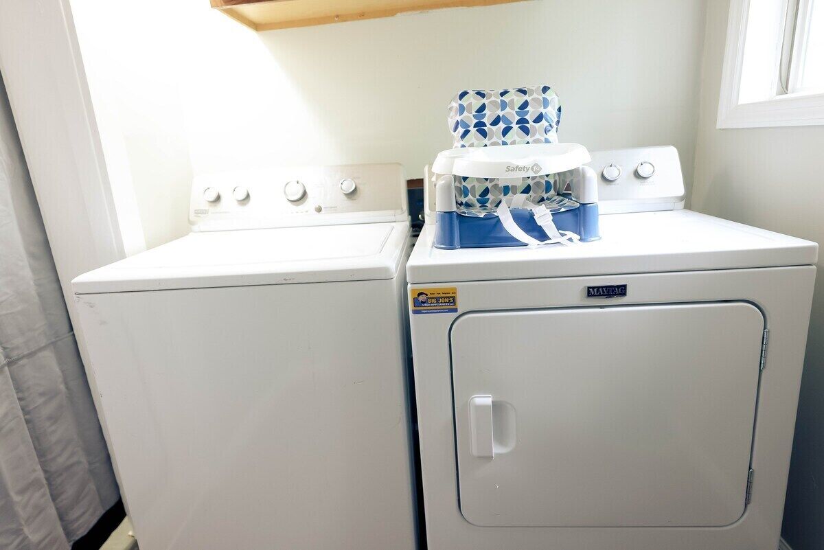 A laundry area with a front-loading washer and dryer, a safety lock on the dryer, and a window above the dryer.