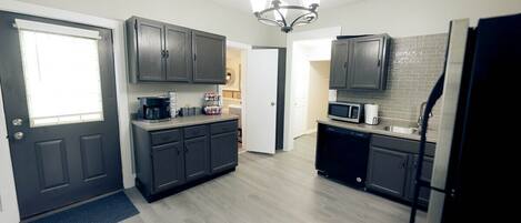 A modern kitchen with dark cabinets, a microwave, a coffee maker, and a dishwasher.
