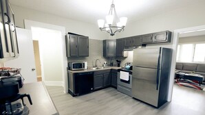 Una cocina moderna con gabinetes grises, un refrigerador de acero inoxidable, un microondas y un lavavajillas.