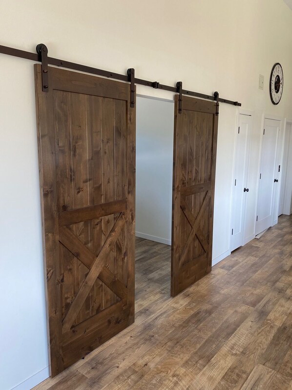 Un couloir avec des portes coulissantes en bois de style grange et des portes blanches.