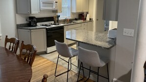 Une cuisine moderne avec des meubles blancs, une cuisinière, un four à micro-ondes et des tabourets de bar.