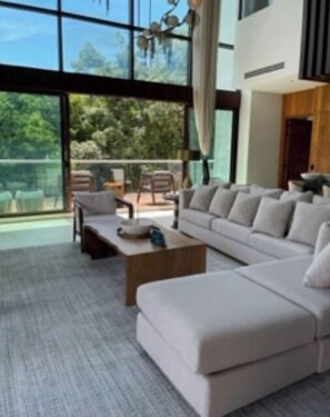 Relax in this stylish living room with a large sofa and coffee table, offering a view of the outdoors from the balcony.