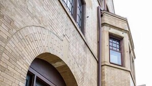 A building with a brick facade, a large arched entrance, and a set of steps leading to the door. - MKE Mansion - East Wing Private Home (Milwaukee)