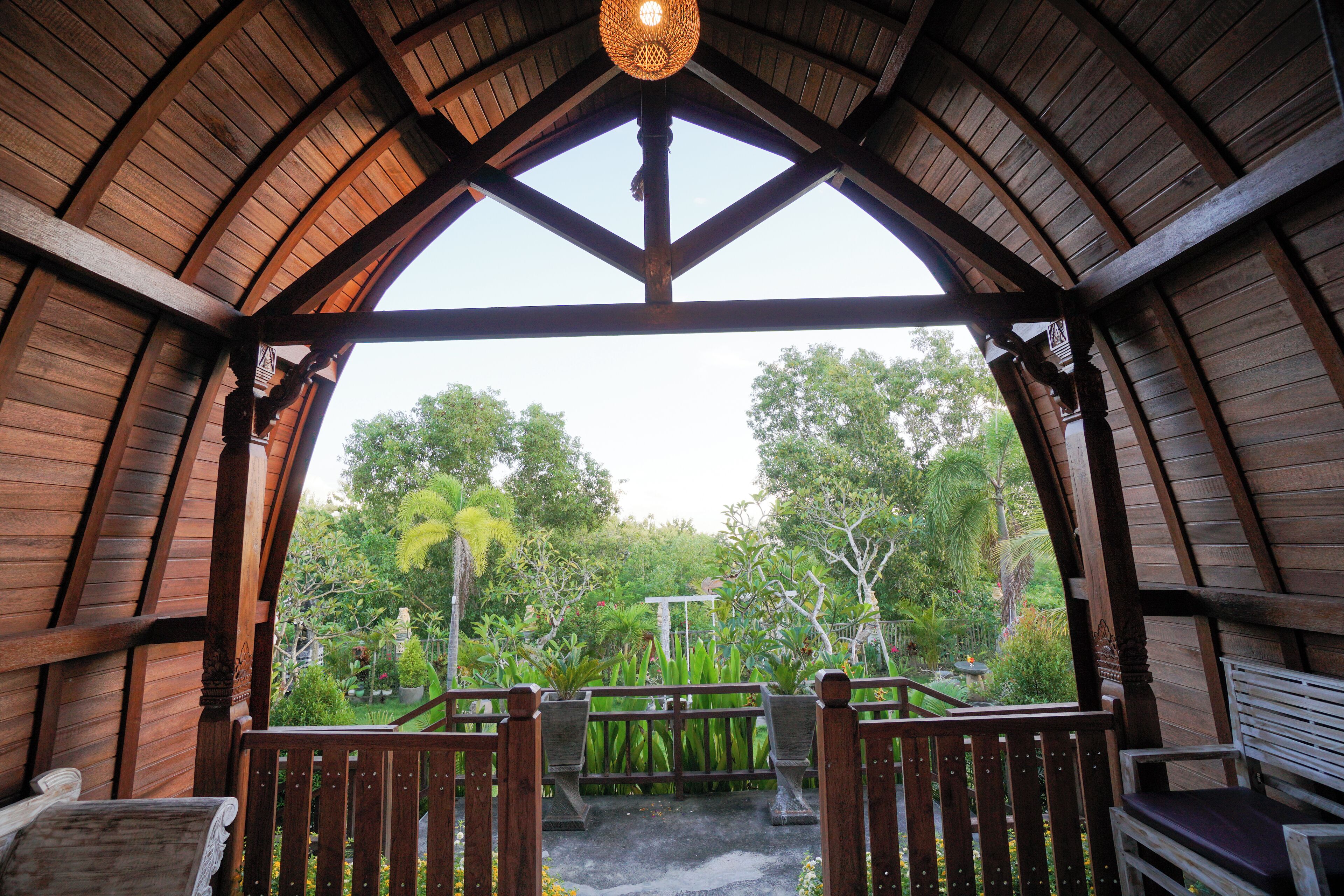 A wooden pavilion with a view of a lush garden.