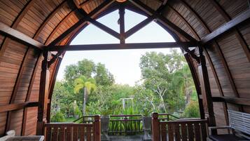 A wooden pavilion with a view of a lush garden.