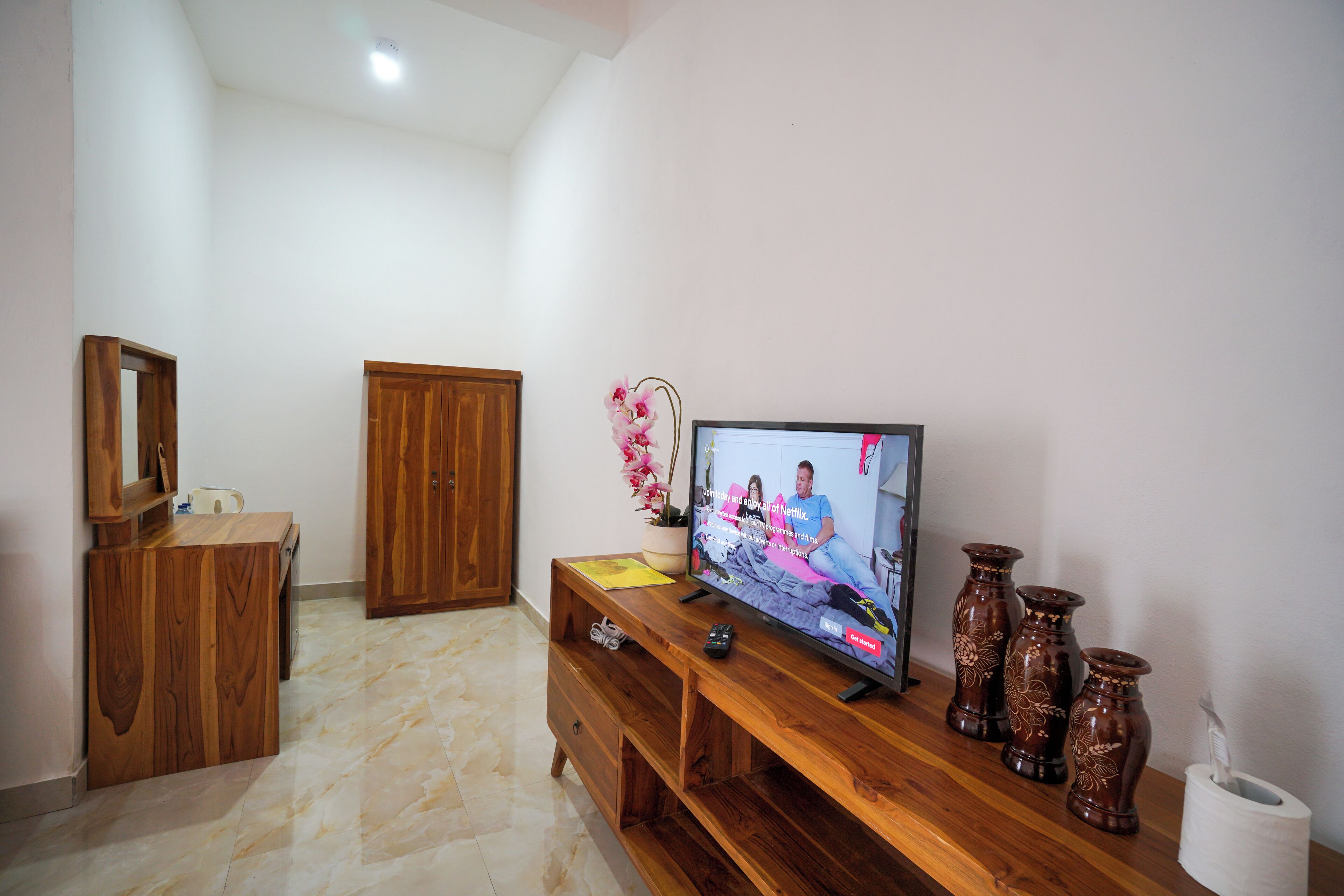 A living room with a wooden entertainment unit, a television, and decorative vases.