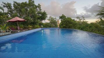 Una piscina al aire libre, sombrillas, tumbonas